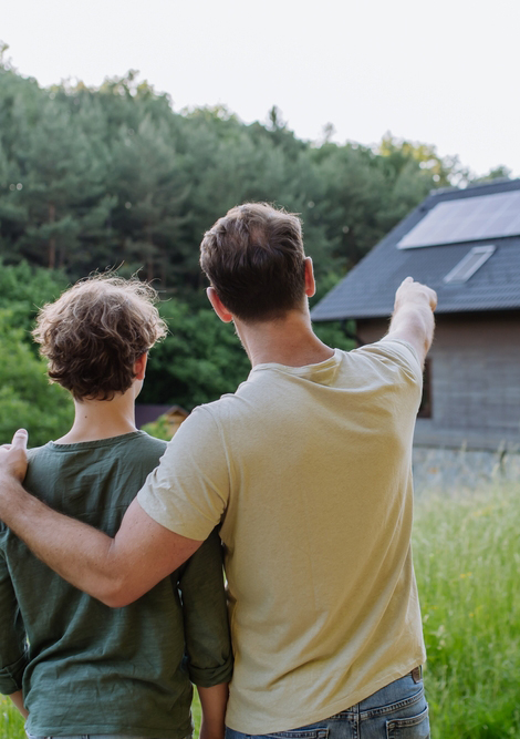 Father showing roof with solar panels to his son. Alternative energy, saving resources and sustainable lifestyle concept.